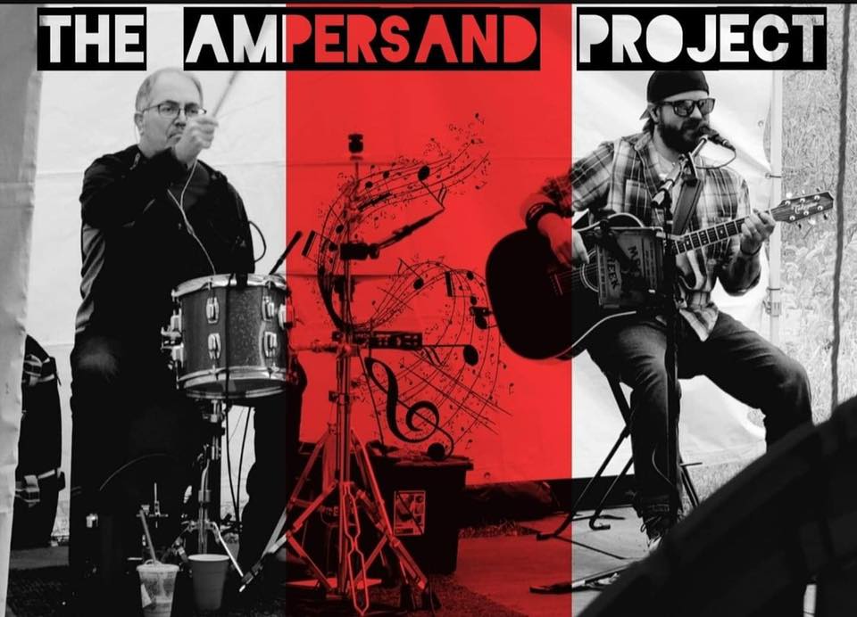 The Ampersand Project band playing drums and guitar.
