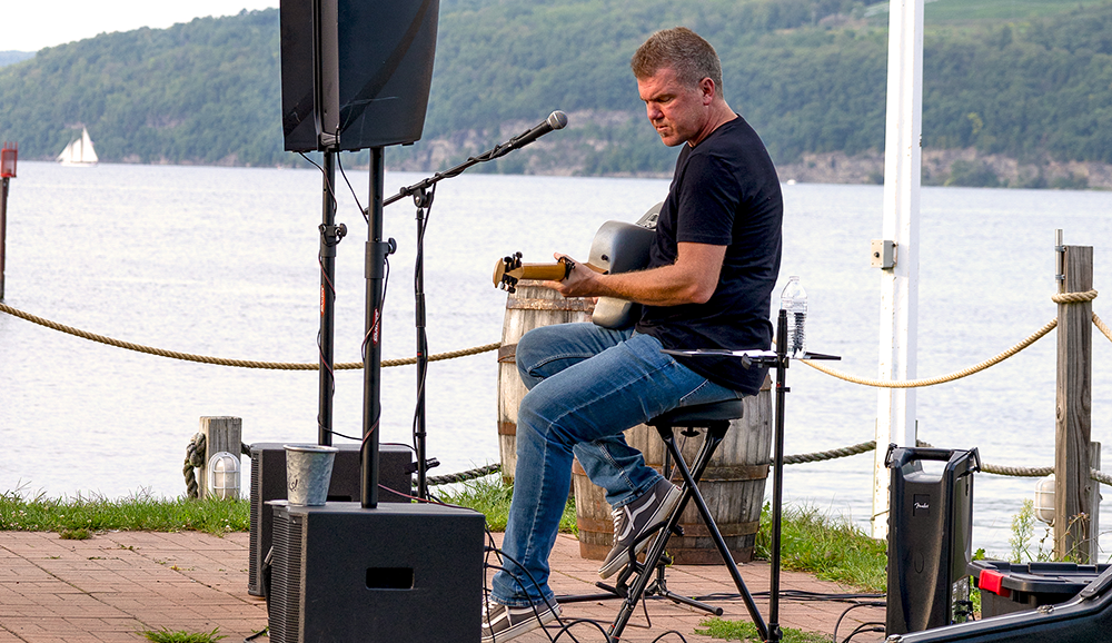 Tremayne Harer playing live music next to lake.