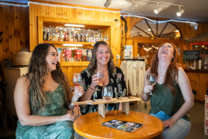 3 Girls laughing and enjoying a wine flight at Hazlitt 1852 Vineyards, Hector, NY.